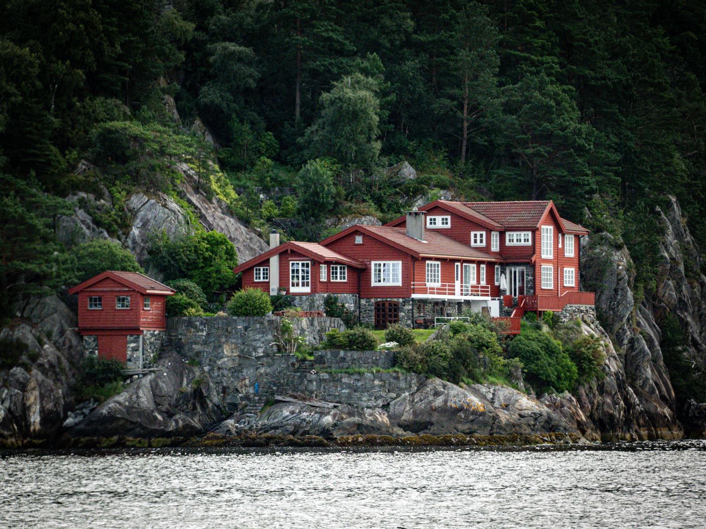 Red-timber villa perched on a rocky coastal cliff along the Norwegian fjords